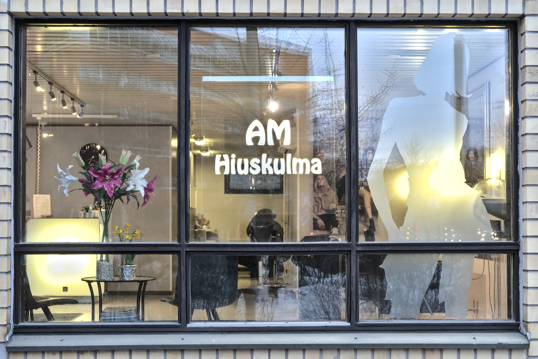 Am Hiuskulman näyteikkuna, jossa liikkeen nimi ja kukat